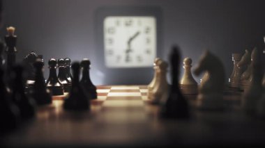 Zaman çizelgeleri. Büyük yakın çekim. Hızla değişen bir çevre ve taşların düzenlendiği bir satranç oyunu. Satranç tahtasının yanında saati gösteren bir saat var. Sahne sıcak ışıkla aydınlatıldı.