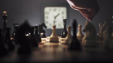 Bir insan ahşap bir satranç tahtasında satranç oynamaya derinden bağlıdır. Siyah ve beyaz satranç taşlarının karmaşık düzenini gösteren büyük yakın çekim. Oyuncu elini hareket ettiriyor, hızlı.