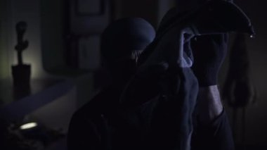 Siyah giysiler, eldivenler ve maske takan ve elinde fener tutan bir hırsız kıyafetleri karıştırıp etrafa saçıyor. Sonra hırsız parlak sarı bir top bulur ve ona şaşırır. Şey...