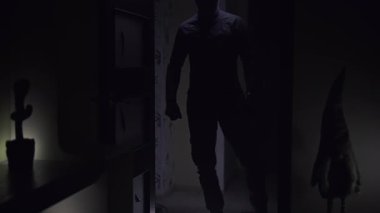 Karanlıktan çıkıp karanlık bir odanın girişinde gizlice ortaya çıkan ve onu bir el feneriyle keşfeden adam. Oda loş bir şekilde aydınlatılmış, tek ışık kaynağı adamın elindeki el feneri. Şey...