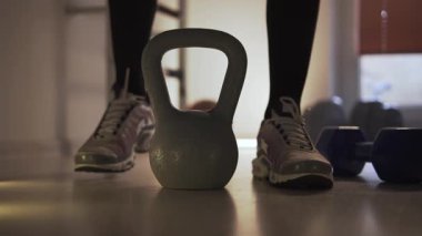 Spor salonunda, spor ayakkabılı bir adam bir kiloya doğru yürür, onu alır ve kaldırır. Spor yaptığı bir fitness merkezinde kalıyor. Arka planda, spor salonunda birkaç dambıl ve bir basketbol topu var.