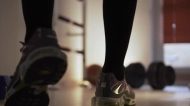 Spor salonunda, spor ayakkabılı bir adam dambıllara doğru birkaç adım atar, durur ve bacaklarını esnetmeye başlar. Antrenman yaptığı bir fitness merkezinde kalıyor. Birkaç dambıl ve bir...