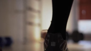 Spor salonunda, spor ayakkabılı bir adam dambıllara doğru birkaç adım atar, yavaşlar, arkasını döner ve bir sonraki adımları düşünür. Antrenman yaptığı bir fitness merkezinde kalıyor. Birkaç dambıl var.