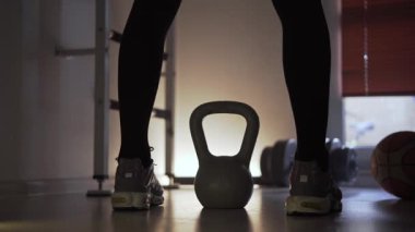 Spor salonunda, spor ayakkabılı bir sporcu su ısıtıcısını kaldırır ve güç egzersizi yapar. Spor yaptığı bir fitness merkezinde kalıyor. Spor salonunun arka planında bir dambıl ve basketbol topu var. Arka ve alt görünüm