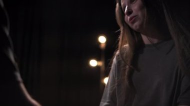 Bir adam ve bir kadın karanlık bir odada karşı karşıya oturuyorlar. Kadın erkeğin elini tutar ve dokunuşuyla onu sakinleştirir ve iletişim kurmasını sağlar. İkisi de gri gömlekli, kadın.