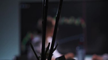 A man and a woman are sitting in front of a computer screen, analyzing stock market charts. The woman, wearing glasses, is focused on the screen, while the man is also actively participating in the