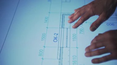 In an office, leaning over a large monitor instead of a desk, a man actively uses an interactive diagram on the screen. The camera focuses on his hand, actively interacting with the engineering