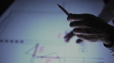 In the office, leaning over a large monitor instead of a desk, a man actively interacts with a drawing on the screen. The camera focuses on his hand, which is wearing a watch and twirling a pencil