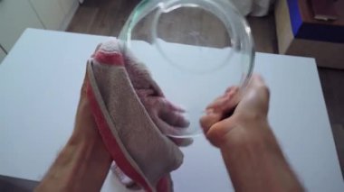 Mutfağın ortasında, masanın yanında bir adam bir elinde cam bir kase tutuyor ve nemden kurtulmak için onu havluyla siliyor. Sonra klozette kir ve nem olup olmadığını kontrol eder.