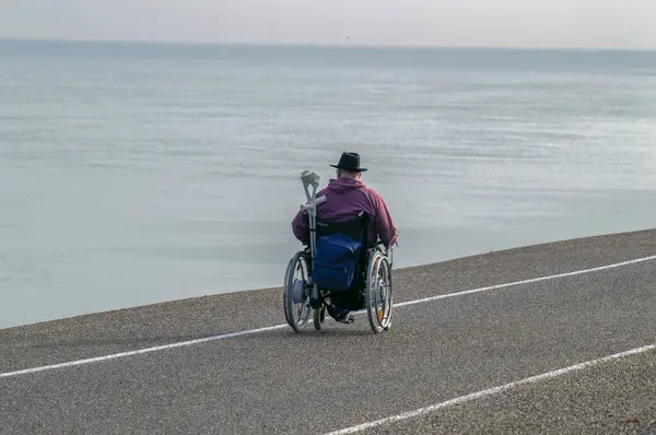 stock image Man In Wheel Chair Along The Sea Promenade At Den Helder The Netherlands 23-9-2019