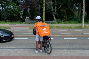 Thuisbezorgd Delivery Man Waiting For A Car At Amsterdam The Netherlands 29-6-2024 clipart