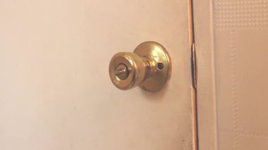 Kıllı adam ön planda bir kapı açarsa beyaz kapının altın kapı kolunu çevirdiği görülebilir..