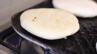 Dökümlü demir tavanın sıcak yüzeyinde mısır keki veya arepa pişiyor..