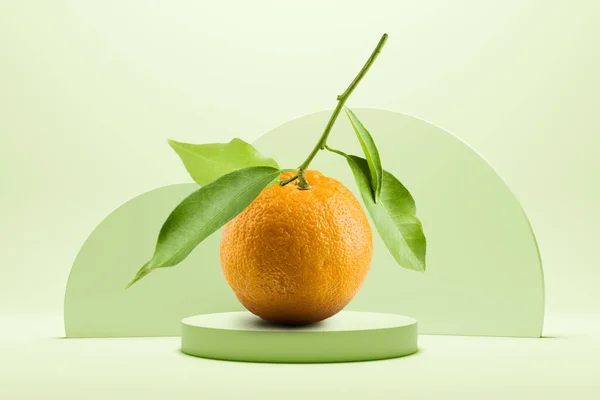 Orange juice with leaves on green background with pedestal.