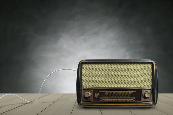 Antique radio on wooden table with concrete wall background.