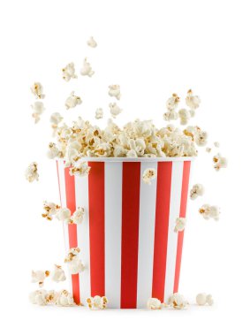 Beyaz arka planda izole edilmiş, kırmızı ve beyaz çizgili konteynırdan düşen patlamış mısır.