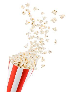 Kırmızı ve beyaz çizgili konteynırdan uçan patlamış mısır, beyaz arka planda izole edilmiş..