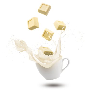 Beyaz çikolata kalıpları beyaz arka planda izole edilmiş kremayla bardağa sıçrıyor..