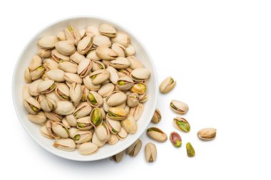 Fıstıklı fındıklar beyaz arka planda kaseye konur. Üst görünüm.