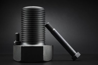 Siyah arka plandaki büyük siyah çelik vidaların çeşitliliği.