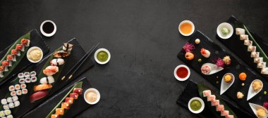 Suşi, pilav, balık ve sosla koyu taştan bir zemin hazırlar. Kopyalama alanı olan üst görünüm.