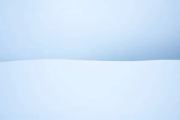 白い雪と柔らかい青と寒い空の曲線の風景のフィールド ロイヤリティフリーのストック写真