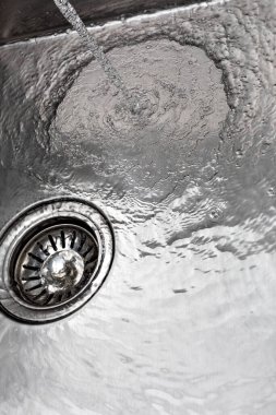 Running water drains down a stainless steel sink