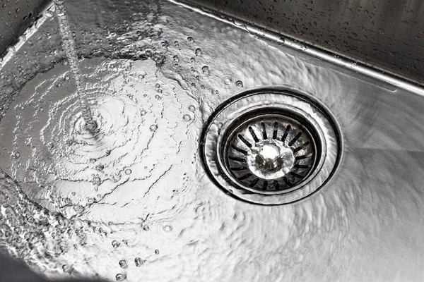 Running water drains down a stainless steel sink