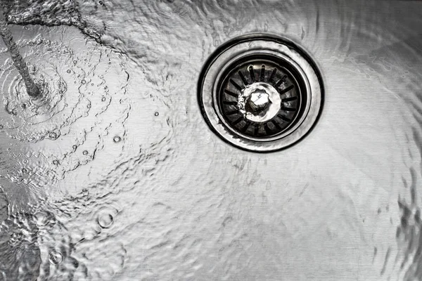 stock image Running water drains down a stainless steel sink