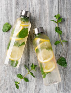 İçi limon dilimleri ve taze nane yapraklarıyla dolu yeniden kullanılabilir iki su şişesi sağlıklı bir yaşam tarzını destekliyor.