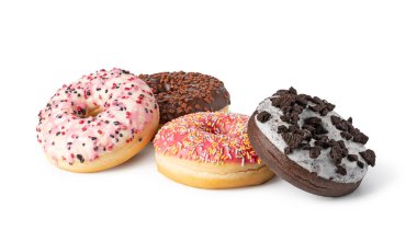 Beyaz arka planda izole edilmiş renkli şeker parçacıkları ve kurabiye kırıntıları ile nefis buzlu donutlar, cezbedici bir tatlı gösterisi yaratıyor.