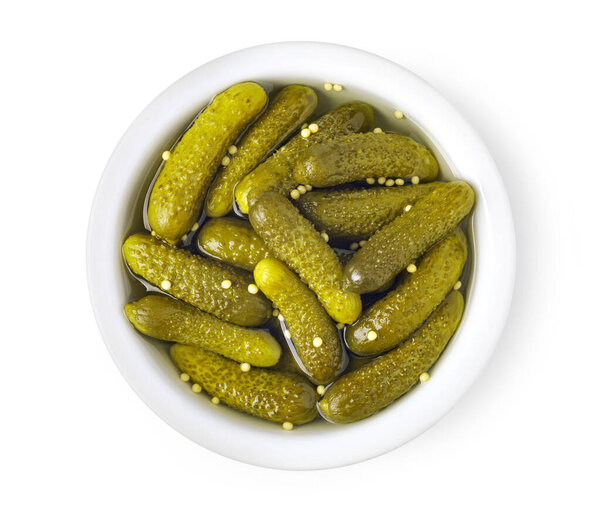 Small pickled cucumbers or gherkins with mustard seeds in a white bowl, forming a delicious appetizer or side dish