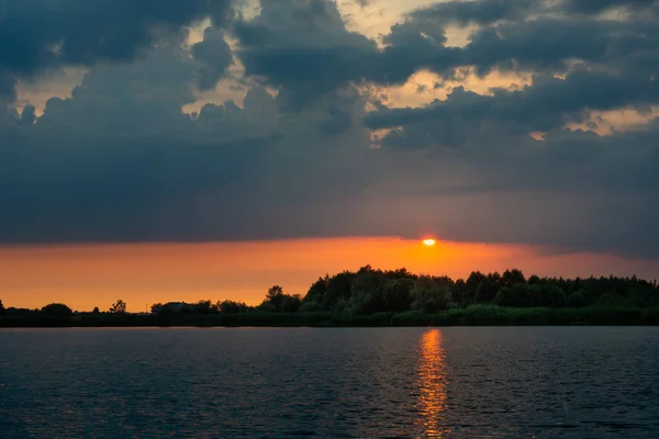 stock image Sunset with dark clouds over the calm lake