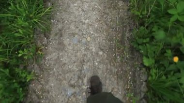 Orman yolunda yürüyen bir adamın bacakları ve ayakkabıları su altında kalmış.
