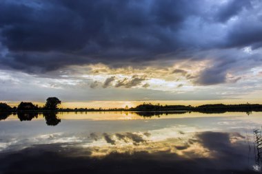 Sakin bir göl üzerindeki bulutlar, yaz akşamı