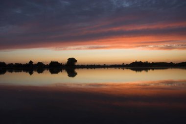 Polonya 'nın doğusunda gün batımında göldeki bulutların yansıması