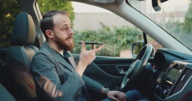 İş adamı modern arabadaki cep telefonuna sesli mesaj kaydediyor. Otomobildeki telefona odaklanmış profesyonel erkek sesli mesaj. Yavaş çekim.