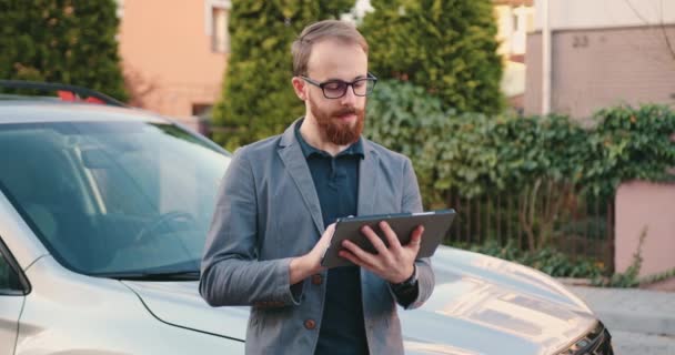 迷人而聪明的成年商人手握平板电脑 站在住宅区停车场的汽车旁边 忙碌的生活方式 — 图库视频影像