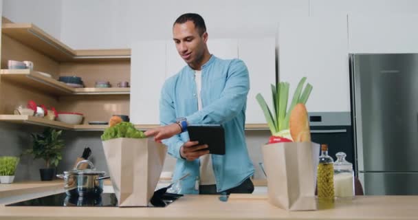 Yakışıklı Bronz Tenli Günlük Kıyafetlerle Gezen Adam Tablet Cihazındaki Listeye — Stok video