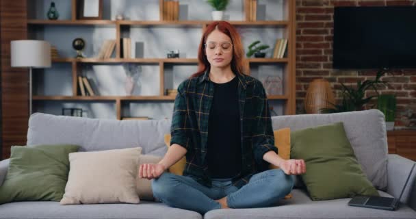Vonzó Indiai Lótuszpozícióban Jógázik Meditáció Csukott Szemmel Otthon Kanapén Gyakorlás — Stock videók