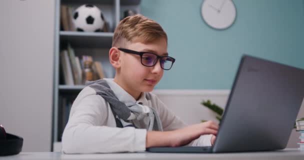 Lachende Schooljongen Bril Met Behulp Van Laptop Zitten Aan Tafel — Stockvideo