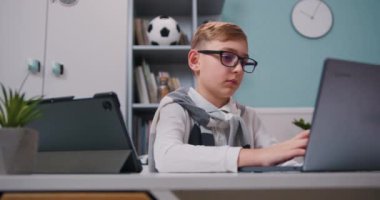 Gözlüklü çocuk evde online eğitim için tablet bilgisayar kullanıyor. Uzaktan eğitim online öğrenme dersi konsepti. Yavaş çekim.