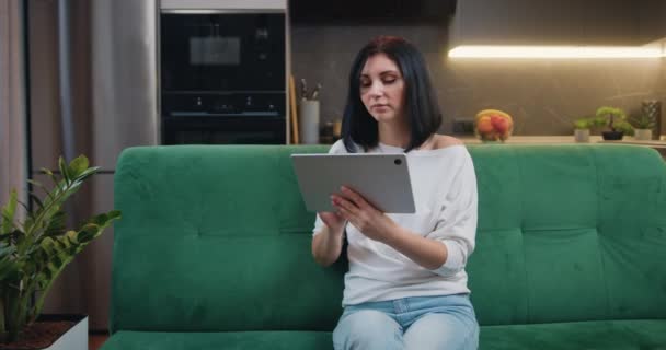 Young Smiling Caucasian Woman Sits Sofa Kitchen Using Digital Tablet — Stok video