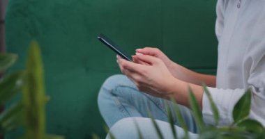 Side view. Close-up. Hands of woman using smartphone mobile social media apps texting messages buying ordering goods in kitchen. Slow motion.