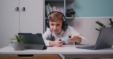 Boy in headphone playing video game with wireless controller with joy of victory. Emotionally winning yes hand gesture victory having fun with controller addiction to videogaming. Slow motion.