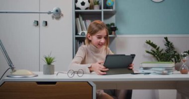 Good-looking happy laughing student girl with tablet pc over home room background. Education, technology and school concept. Slow motion