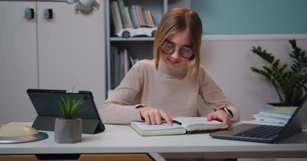 学ぶ前に 美しくスマートな白人10歳の少女は 自宅の職場で机に座って勉強し 本を読んでいます スローモーション — ストック動画