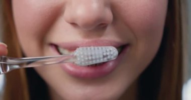 Close Up. Oral hygiene for braces. Teen girl cleaning and brushing teeth with clear ceramic braces using special brushing tools. Slow motion.
