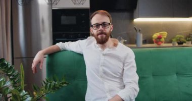 Portrait of a cheerful smiling caucasian handsome man looking at camera and posing against white kitchen background. Slow motion.