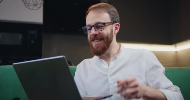 戴眼镜的大胡子男子在远程工作场所的笔记本电脑上打电话给视频聊天 男子在现代厨房举行在线视频电话会议 慢动作 — 图库视频影像